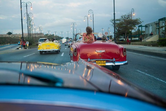 Tourists riding antique cars through Havana, Cuba.